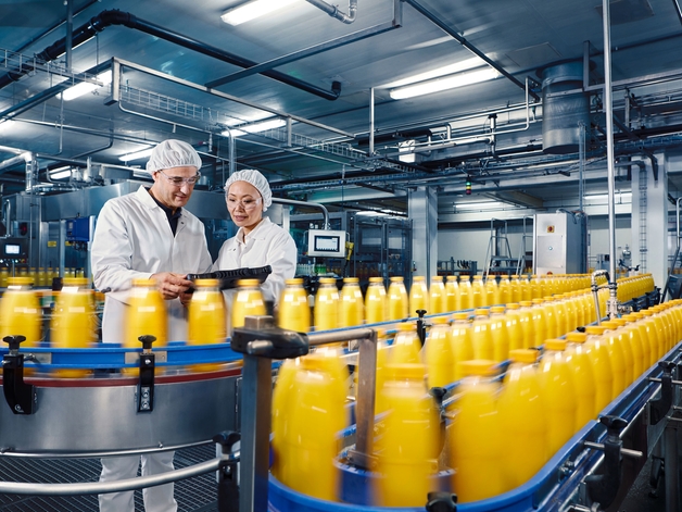飲料プラントでオレンジジュースの充填プロセスを管理する2人のエンジニア。